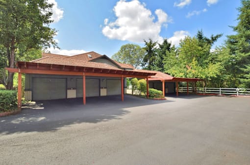 A large building with a red roof and a parking lot in front.