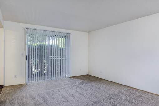 the living room of an apartment with a door to a patio