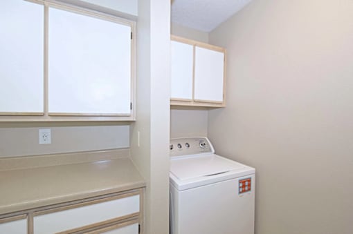 A white dryer is in a small room with a window and a counter.