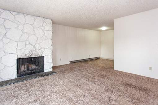 an empty living room with a fireplace and a carpeted floor