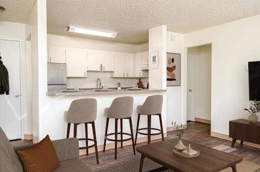A kitchen with white cabinets and a countertop with a sink and a refrigerator.