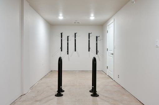 a room with white walls and a beige floor with black poles in the middle of it