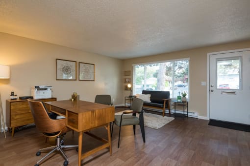 Pinewood Terrace Apartments | Leasing Office Model showing entrance, office desk, three chairs and a sitting couch.