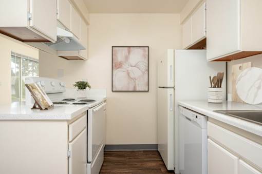 A kitchen with white appliances and a fridge.