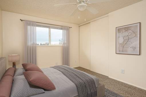 A bedroom with a large bed and a ceiling fan.