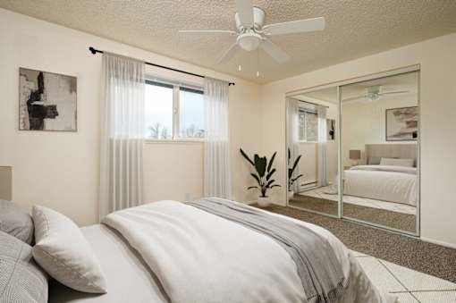 A bedroom with a large bed and a ceiling fan.