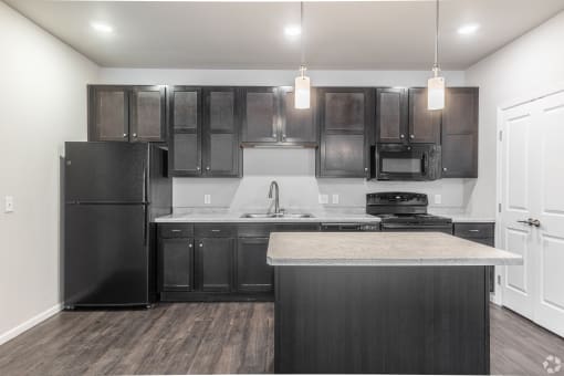 an empty kitchen with black appliances and dark wood cabinets