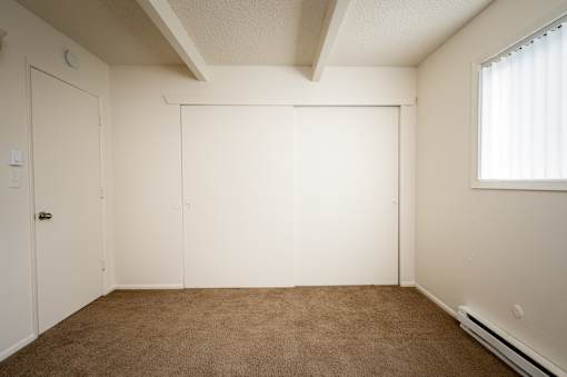 A room with a brown carpet and white walls.