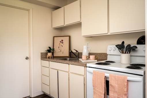 A kitchen with white cabinets and a white stove top oven.