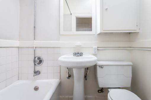 A white bathroom with a tub, toilet, and sink.