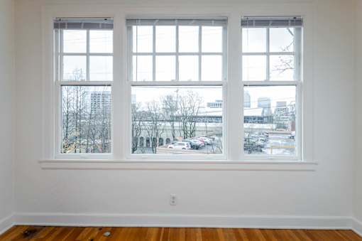 A room with a large window overlooking a parking lot and buildings.