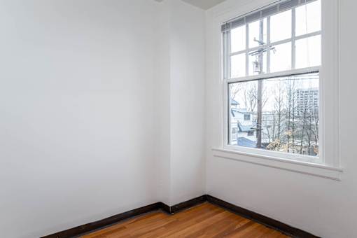 A room with a window and a wooden floor.