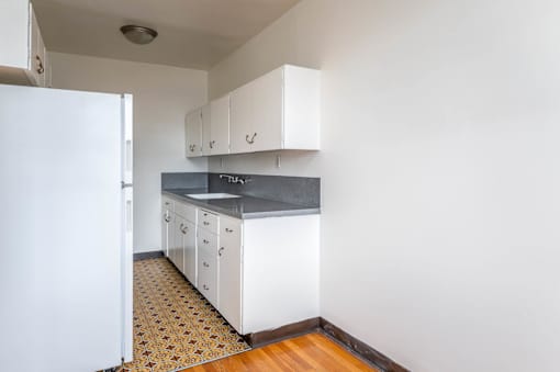 A kitchen with white cabinets and a patterned floor.