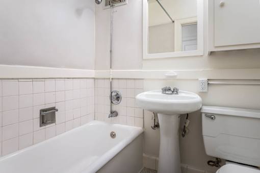 A white bathroom with a tub, sink, and mirror.