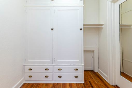 A white wardrobe with four drawers is in a room.