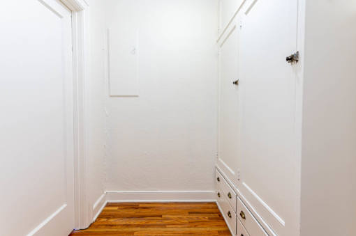 A white hallway with a wooden floor and white walls.