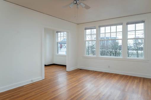 A room with a ceiling fan and two windows.