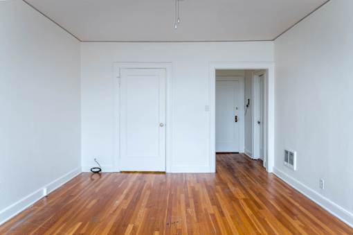 A room with wooden floors and two white doors.