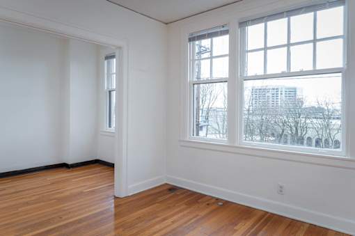 A room with a large window and wooden floors.