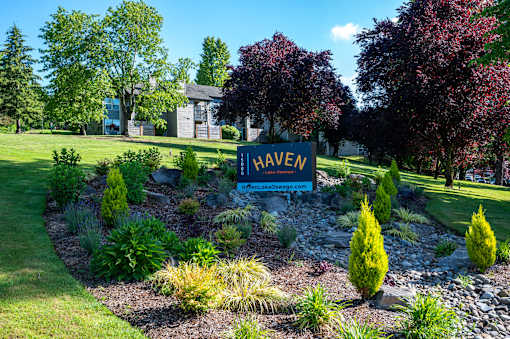 A garden with a sign that says "HAVEN" in front of a house.
