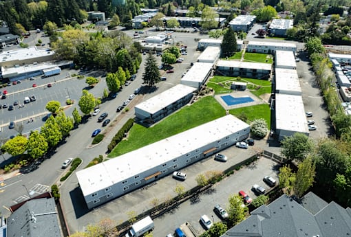 A parking lot with cars and a building with a pool in the background.