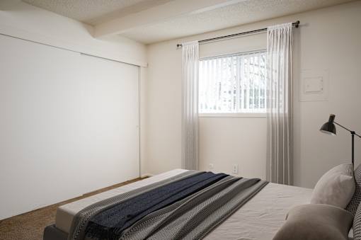 A bedroom with a bed, pillows, and a window with curtains.