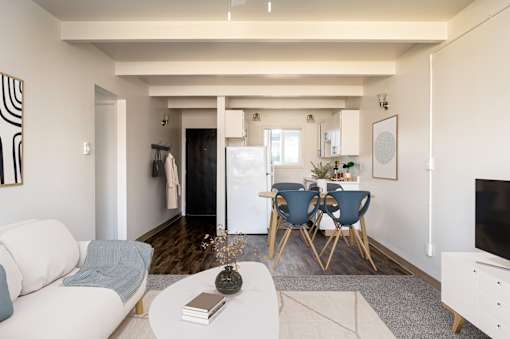 A living room with a white sofa, a grey rug, a white coffee table, a blue chair and a white cabinet.