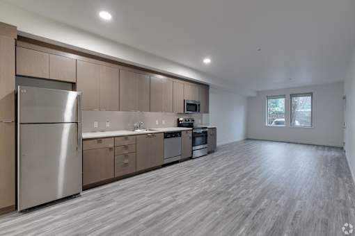 A modern kitchen with wooden floors and stainless steel appliances.