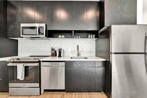 A modern kitchen with a stainless steel refrigerator, oven, and sink.