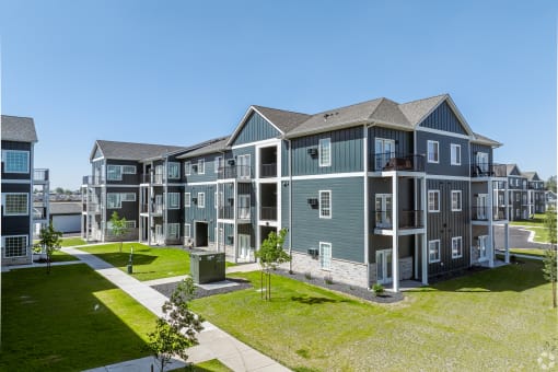 an image of an apartment building with green grass and a sidewalk