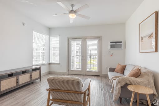 a living room with a couch and a chair and a ceiling fan