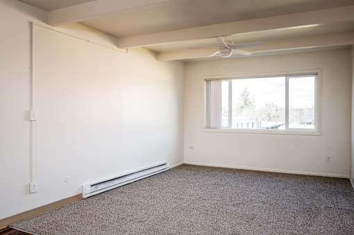 A room with a window and a fan on the ceiling.