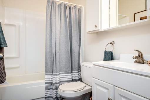 A white bathroom with a toilet, sink, and shower curtain.