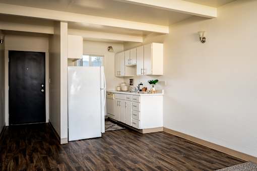 A kitchen with white appliances and wooden floors.