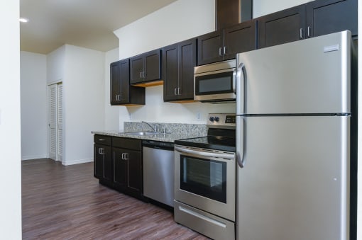 Kitchen with dark cabinetry and stainless steel refrigerator, stove/oven, microwave and dishwasher.