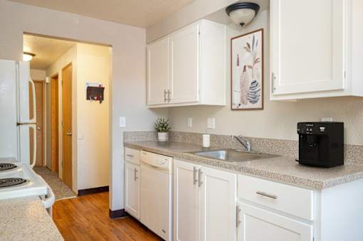 A modern kitchen with white cabinets and a black coffee maker.