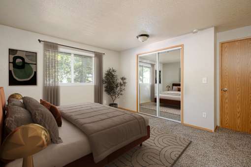 A bedroom with a bed, chair, and mirror.
