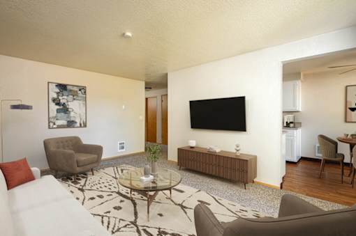 A living room with a white couch, a coffee table, and a television.