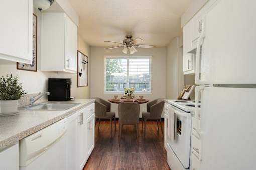 A kitchen with white appliances and wooden floors.