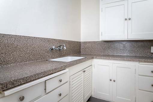 A kitchen with white cabinets and a granite countertop.