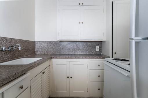 A kitchen with white cabinets and a granite countertop.