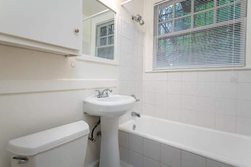 A white bathroom with a sink, toilet and bathtub.