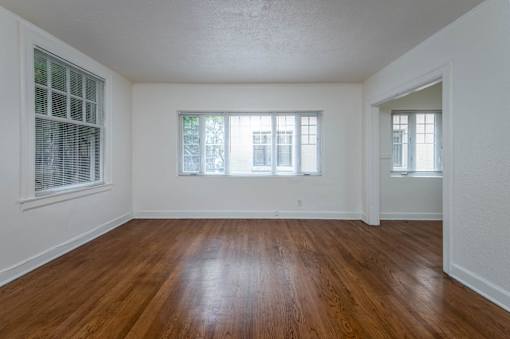 A room with wooden floors and three windows.