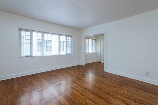 A room with wooden floors and two windows.