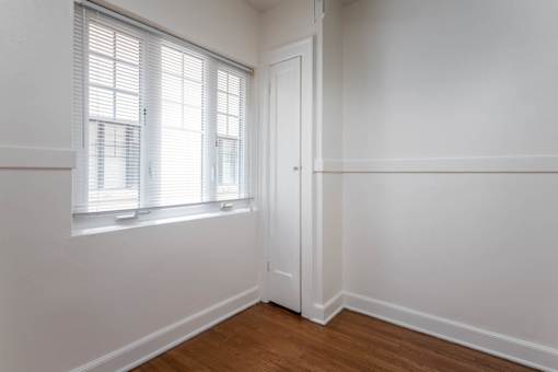 A room with a white door and a window with blinds.