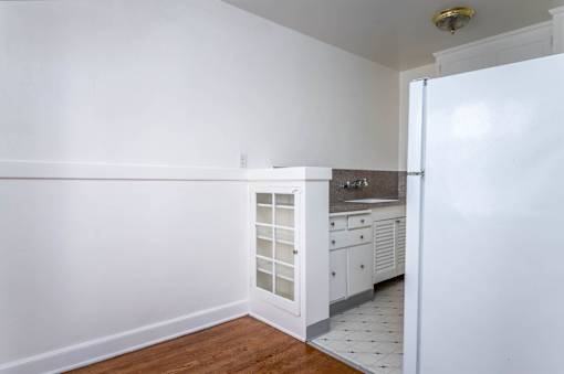 A kitchen with white cabinets and a white refrigerator.