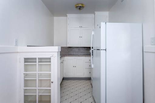A kitchen with white cabinets and a white refrigerator.