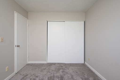 an empty bedroom with white walls and a closet