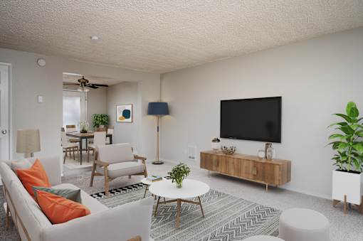 A living room with a white couch, a coffee table, and a television.