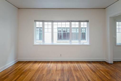 A room with a large window and wooden floors.